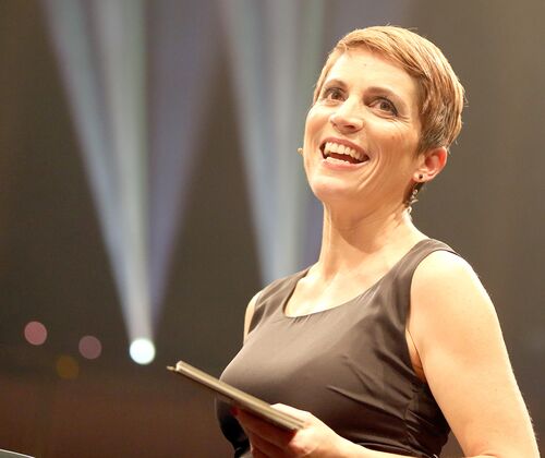 Moderatorin Miriam Deforth lachend mit Moderationkarten auf der Bühne